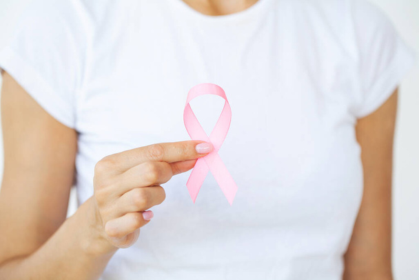 Woman using pink ribbon to support breast cancer cause or AIDS - Photo, Image