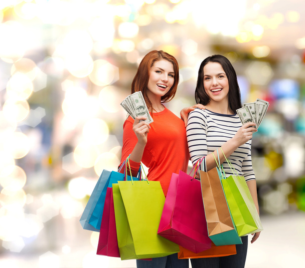 Smiling teenage girls with shopping bags and money - Foto, immagini