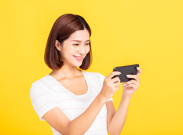 スマートフォンを見てオンラインでゲームをプレイする若い女性 - 写真・画像
