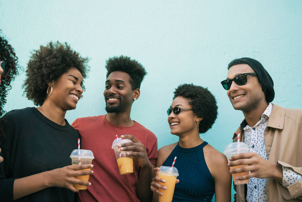 Portrait of afro friends having fun together and enjoying good time while drinking fresh fruit juice.  - Foto, Bild