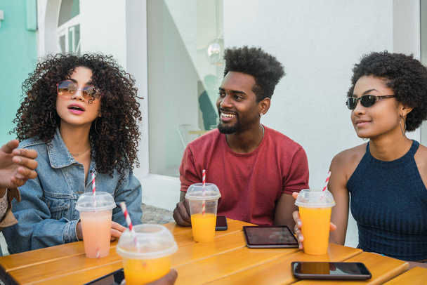 Portrait of Afro friends having fun together and enjoying good time while drinking fresh fruit juice. - 写真・画像