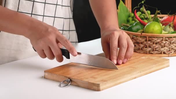 Nainen leikkaa Tuore Red Chilli paloiksi veitsellä puinen leikkuulauta. - Materiaali, video