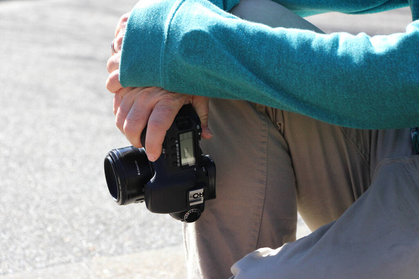 Mladý muž fotograf odpočívá a drží fotoaparát v slunečný den - Fotografie, Obrázek