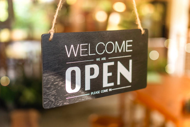 A business sign that says open on cafe or restaurant hang on tree at entrance of shop with sun light bokeh background - Photo, Image