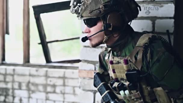 Homme militaire avec fusil d'assaut debout à l'intérieur du bâtiment, il est prêt pour le combat - Séquence, vidéo