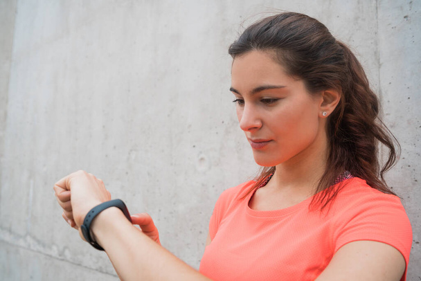 Portrait of a fitness woman checking time on her smart watch. Sport and healthy lifestyle concept. - Foto, Bild