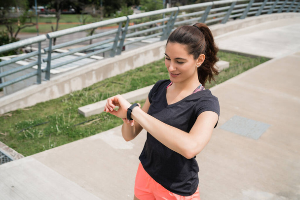 Portrait of a fitness woman checking time on her smart watch. Sport and healthy lifestyle concept. - Φωτογραφία, εικόνα