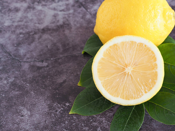 Cerrar Medio limón con hojas verdes sobre fondo gris oscuro con espacio para copiar. Vitamina C alta, que ayuda a controlar el peso y reducir el riesgo de cáncer. Copiar espacio para texto - Foto, Imagen