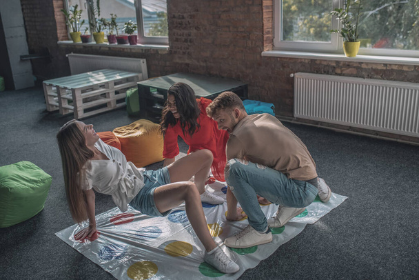 Three friends playing twister on the floor - Foto, imagen