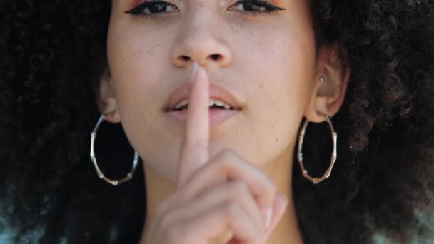 Close-up portret van mooi meisje met afro en serieus gezicht, met haar wijsvinger op haar lippen en mond. Afro-Amerikaanse vrouw vraagt om kalmte, stilte gebaar. Geheimen bewaren, privacy. - Video