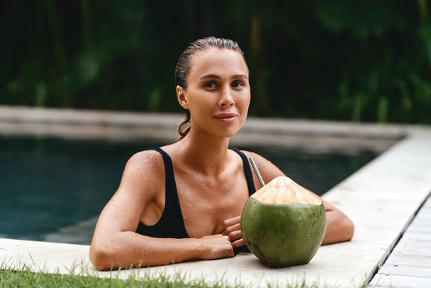 retrato de menina bonito com coquetel de coco na piscina tropical. - Foto, Imagem
