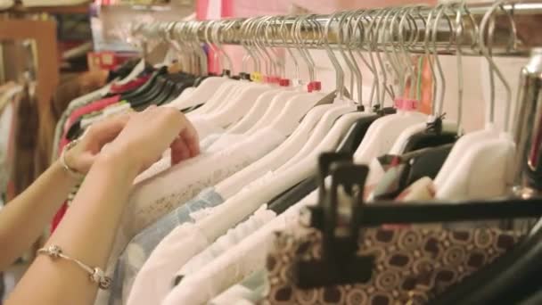 mains de fille choisir vêtements sur cintres vente - Séquence, vidéo