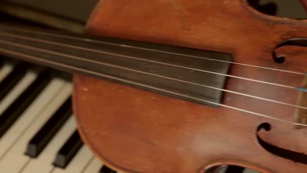 régi hegedű fekszik a zongora billentyűkön stradivarius hegedű vintage hangszerek - Felvétel, videó