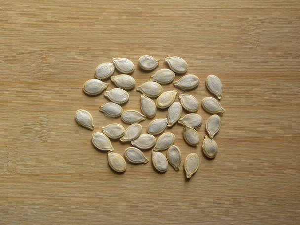 Pumpkin seeds on wood background - Фото, изображение