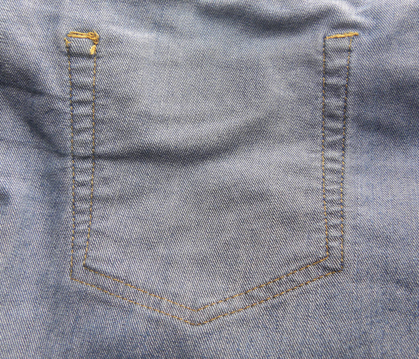 Задній бік стібків задньої кишені блакитних джинсів
 - Фото, зображення