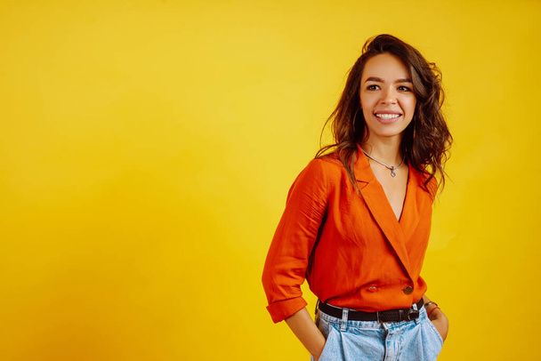 Portrait of young woman in a shirt and jeans. African American woman posing on yellow background. Fashion, glamour and lifestyle concept. - Photo, Image