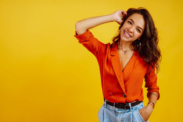 Portrait of young woman in a shirt and jeans. African American woman posing on yellow background. Fashion, glamour and lifestyle concept. - Фото, зображення