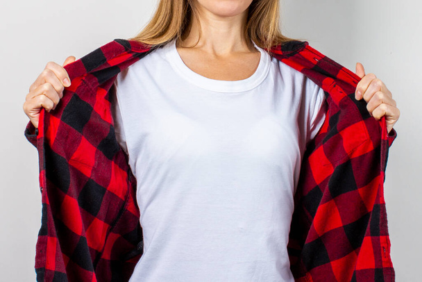 Mujer joven con una sonrisa en una camisa roja y camiseta blanca sobre un fondo blanco. Plantilla conceptual para texto, logo, shock, sorpresa. Banner. - Foto, imagen