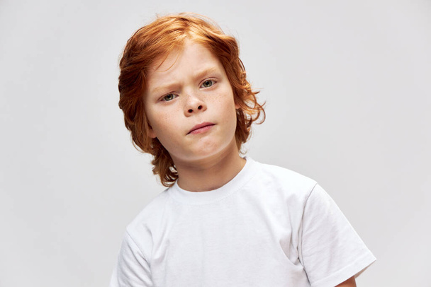 Rudowłosy chłopiec z niezadowolonym wyrazem twarzy biały t-shirt przycięty widok - Zdjęcie, obraz