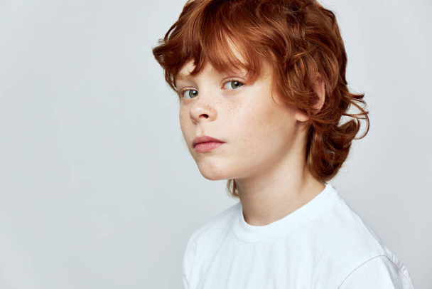 Rothaarige Kindergesichter Nahaufnahme abgeschnittener Blick auf weiße T-Shirt-Sommersprossen im Gesicht - Foto, Bild