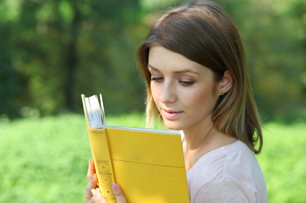 Blonde girl reading a book in the park - Foto, immagini