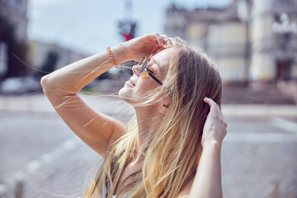 Foto cerrada de una guapa pelirroja con gafas de sol que cierra los ojos y se toca la cabeza  - Foto, Imagen