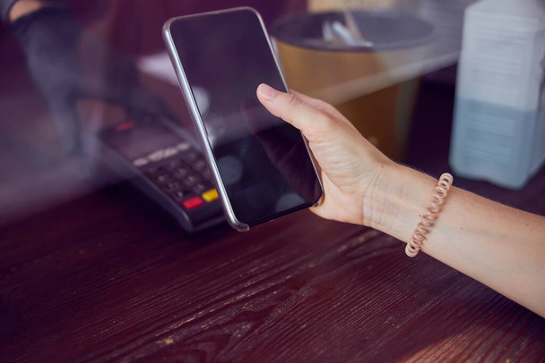  Primer plano de una mano con un scrunchy de mujer joven sosteniendo un teléfono inteligente  - Foto, imagen