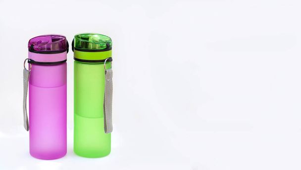 Dwie butelki sportowe (pijący) z wodą izolowaną na białym tle. Koncepcja picia czystej wody - Zdjęcie, obraz