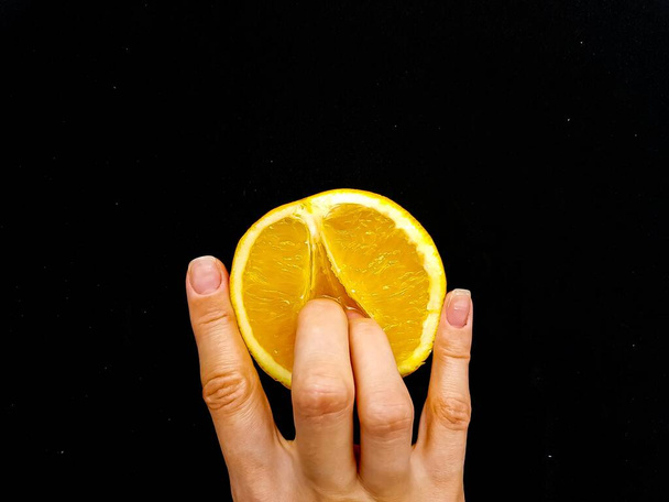 Sex concept. A vagina symbol. Fingers on an orange on a black background. - Фото, изображение