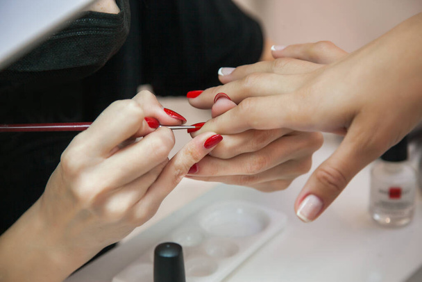 Gel polish design. Female master in the salon is painting with brush on the hands of the client. Beauty industry, creativity concept. - Photo, image