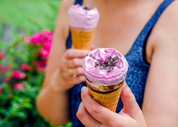 Морозиво в вафельному конусі в руках жінки, влітку в парку
 - Фото, зображення