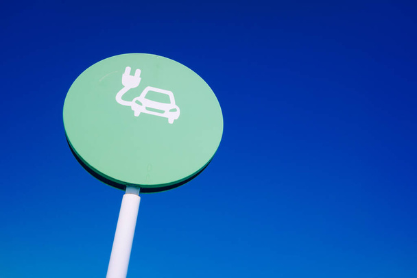 Rundes Zeichen der Ladestation für Elektroautos mit blauem Himmel und Kopierraum. - Foto, Bild