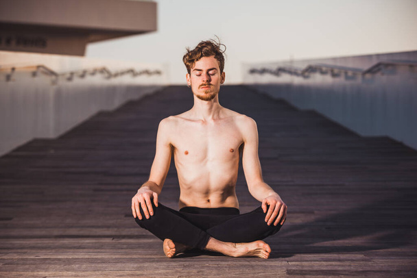 Young man practices yoga to relax from the stress of the city and exercise. - Photo, Image