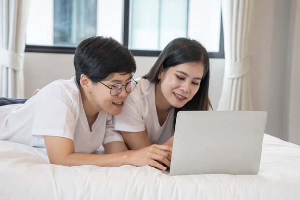 Coppia femminile e una donna libanese giocano insieme un social network e ordinano i loro acquisti online con il loro laptop nella loro camera da letto.. Concetto LGBT e bisessuale - Foto, immagini