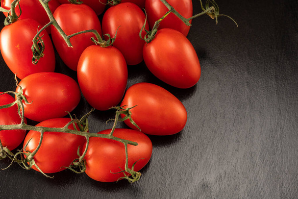 Pomidory wiśniowe na czarnym tle zbliżenie - Zdjęcie, obraz