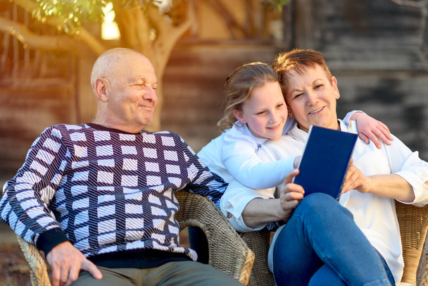 Прекрасна щаслива бабуся і дідусь читання онуці Книга в природі на заході сонця
. - Фото, зображення