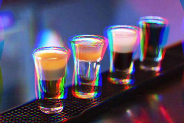 Rövid italok az éjszakai bárban. Négy pohár alkoholos koktél. Absztrakt kép hibás művészeti hatásokkal és zajjal. - Fotó, kép