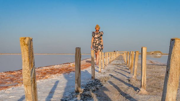 Happy woman in a beautiful dress, young with gentle lips on the background of a salt lake in hot sunny weather - Foto, Bild