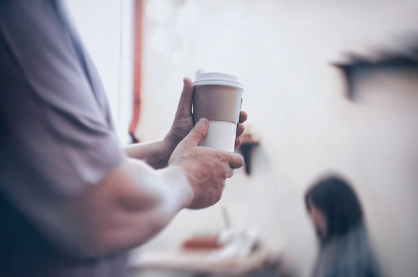 Man holds in his hand a mockup of an ecological paper cup for coffee in a restaurant - Valokuva, kuva