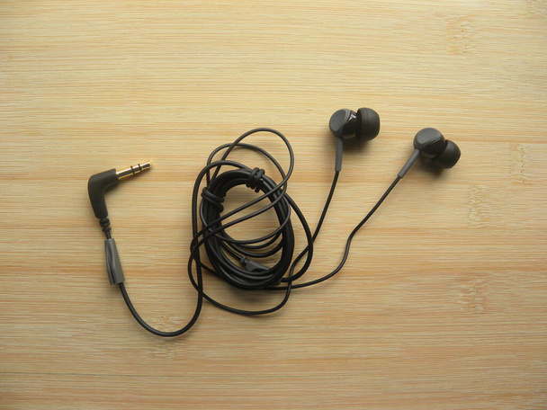 Czarne słuchawki dokanałowe na drewnianym stole - Zdjęcie, obraz