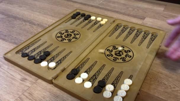 Szczegóły gry backgammon z dwóch kości zbliżenie. Mężczyzna rzuca dwiema kostkami i przesuwa warcaby na pokładzie. Młodzi ludzie grają w tryktraka podczas relaksu. 4k. - Materiał filmowy, wideo