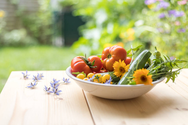 Fresh colorful vegetables in a bowl, raised in the own garden. Tomatoes, zucchini, flowers and herbs. - Zdjęcie, obraz