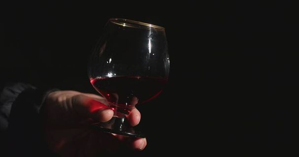 Sommelier in front of a black background tastes red wine - Foto, imagen