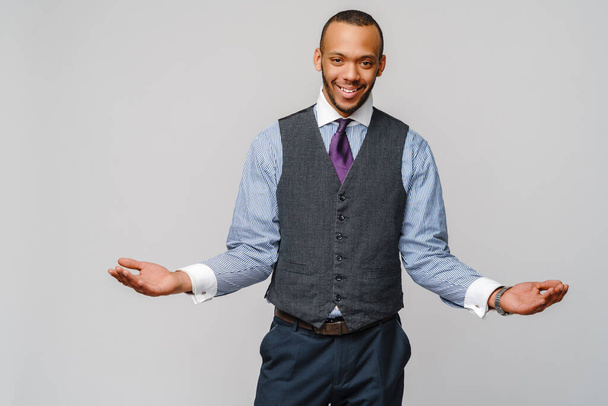 Cheerful smiling happy young african american businessman wearing tie over light grey background looking at the camera smiling with open arms for hug - Фото, изображение