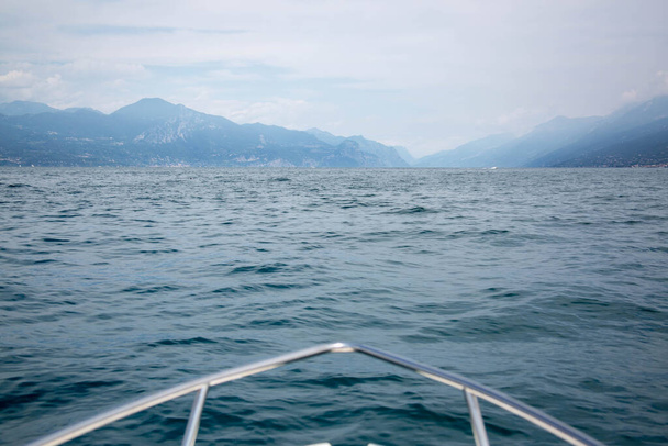 πανόραμα του νησιού στη λίμνη Garda, Ιταλία, θέα στο σκάφος με μπλε νερά και συννεφιασμένο ουρανό - Φωτογραφία, εικόνα