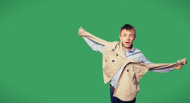 Portrait of amazed young man with jacket over green background - Фото, зображення