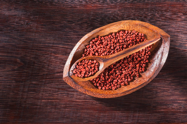 Annatto-Samen in Schale auf Holzgrund - Bixa Orellana. - Foto, Bild