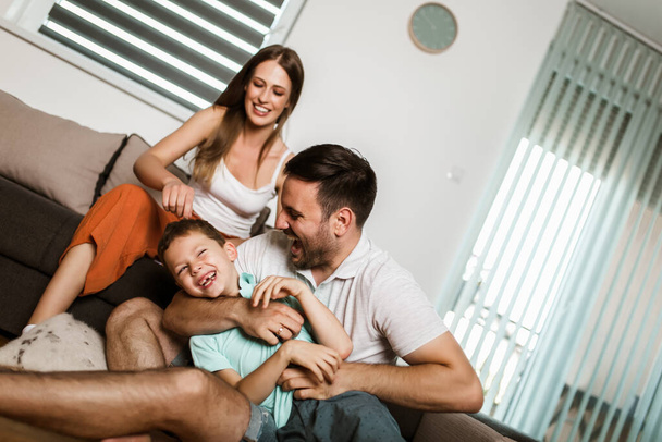 Giovane bella famiglia in look casalingo si trova su un tappeto accogliente nel soggiorno. - Foto, immagini