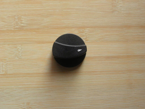 Plástico de color negro On Off Pomo de cocina de gas mantenido en la mesa de madera - Foto, imagen
