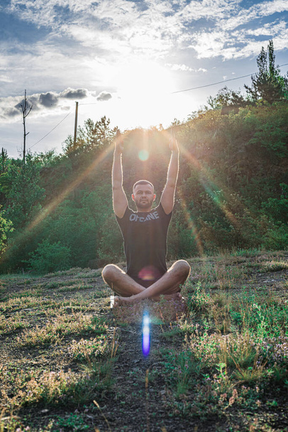 Silhueta de corpo perfeito homem age ioga na rocha com fundo do pôr do sol. Dia Internacional do Yoga
. - Foto, Imagem